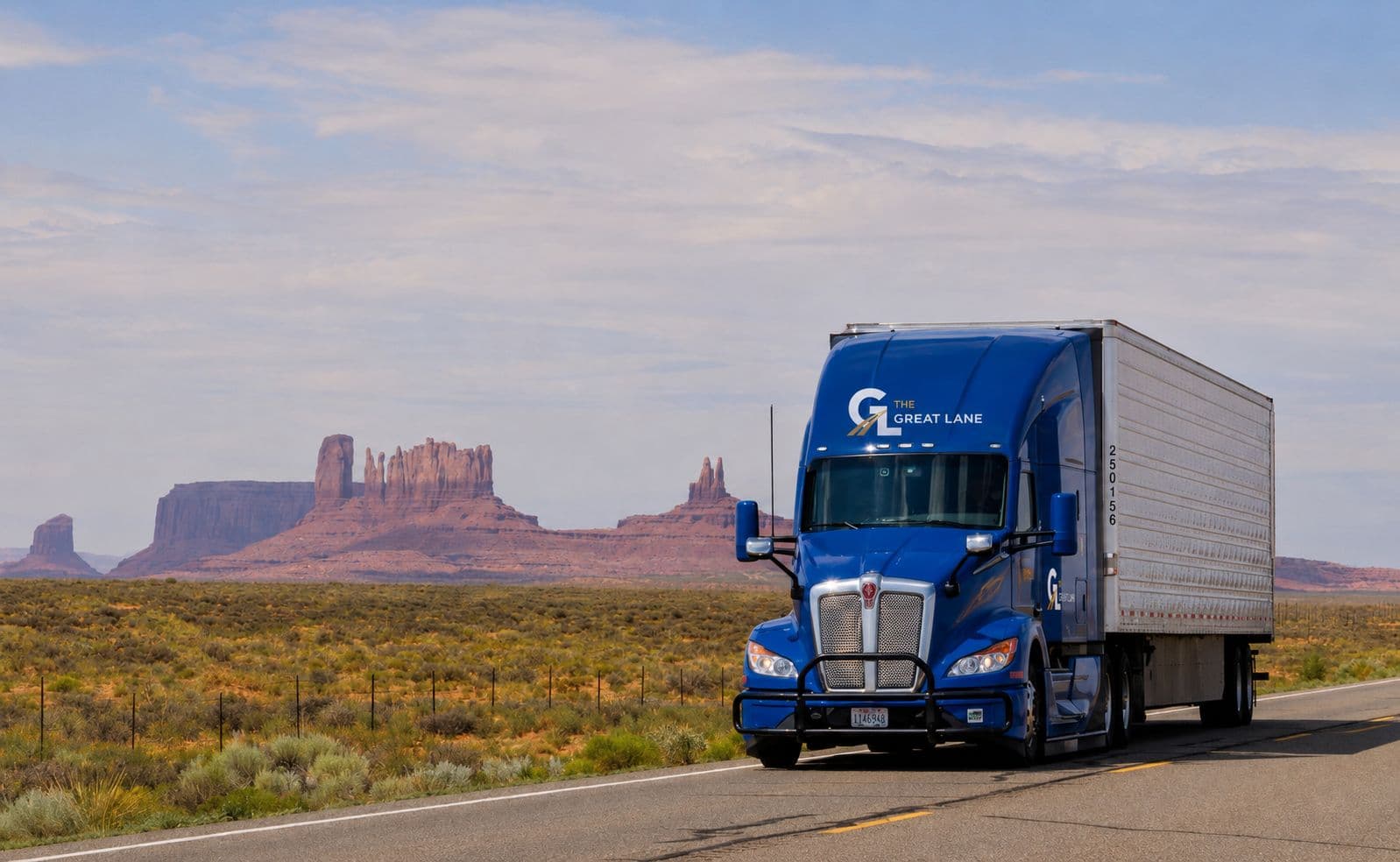 Blue Great Lane tractor with white trailer on a desert highway, brand mark on the sleeper fairing