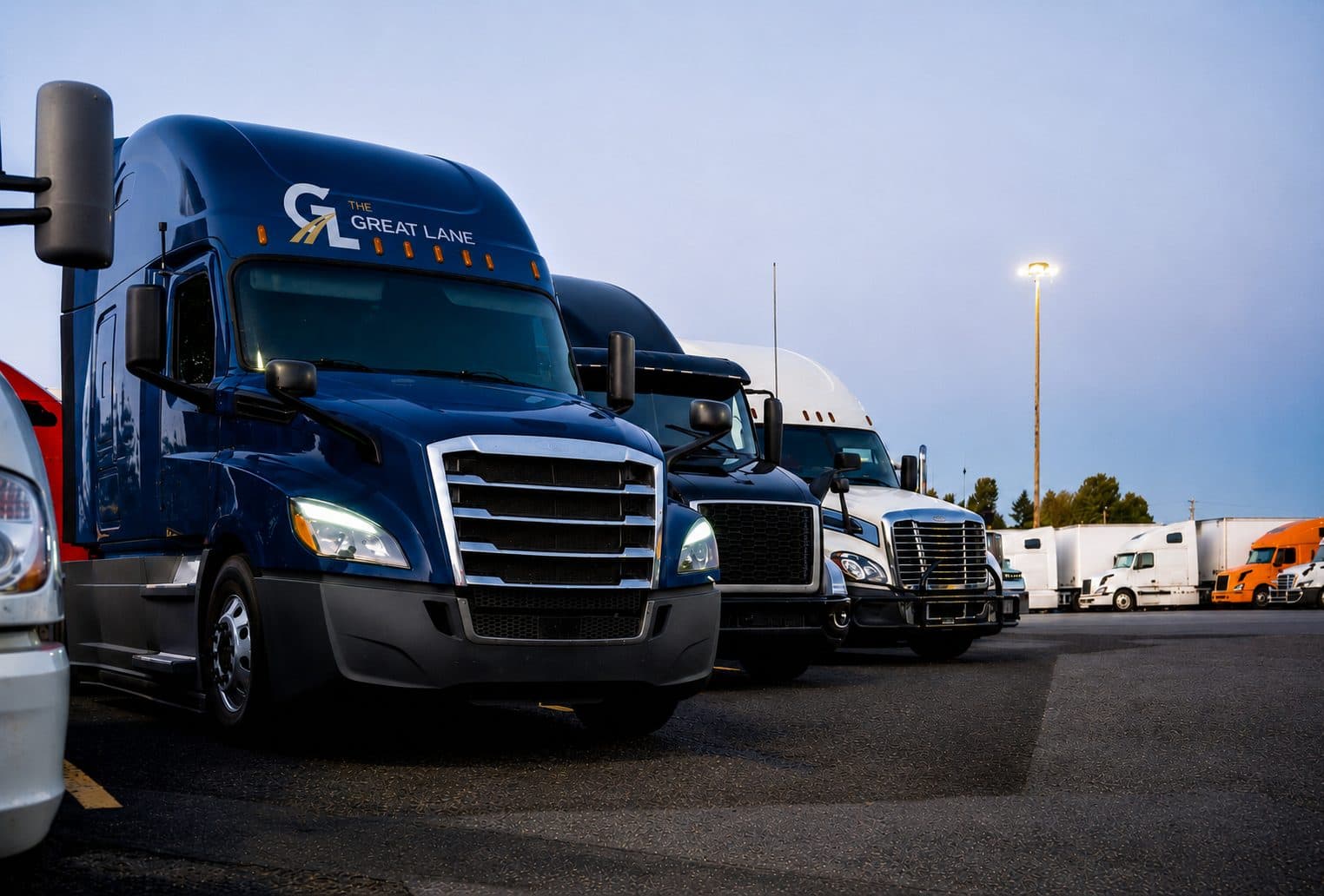 Great Lane branded navy tractor among other trucks in a dusk parking lot